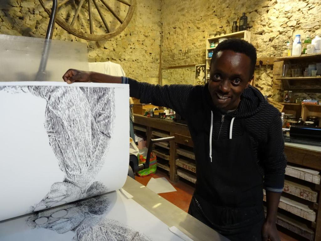 Evans Mbugua working on the lithography press. Photo credit Atelier le Grand Village.